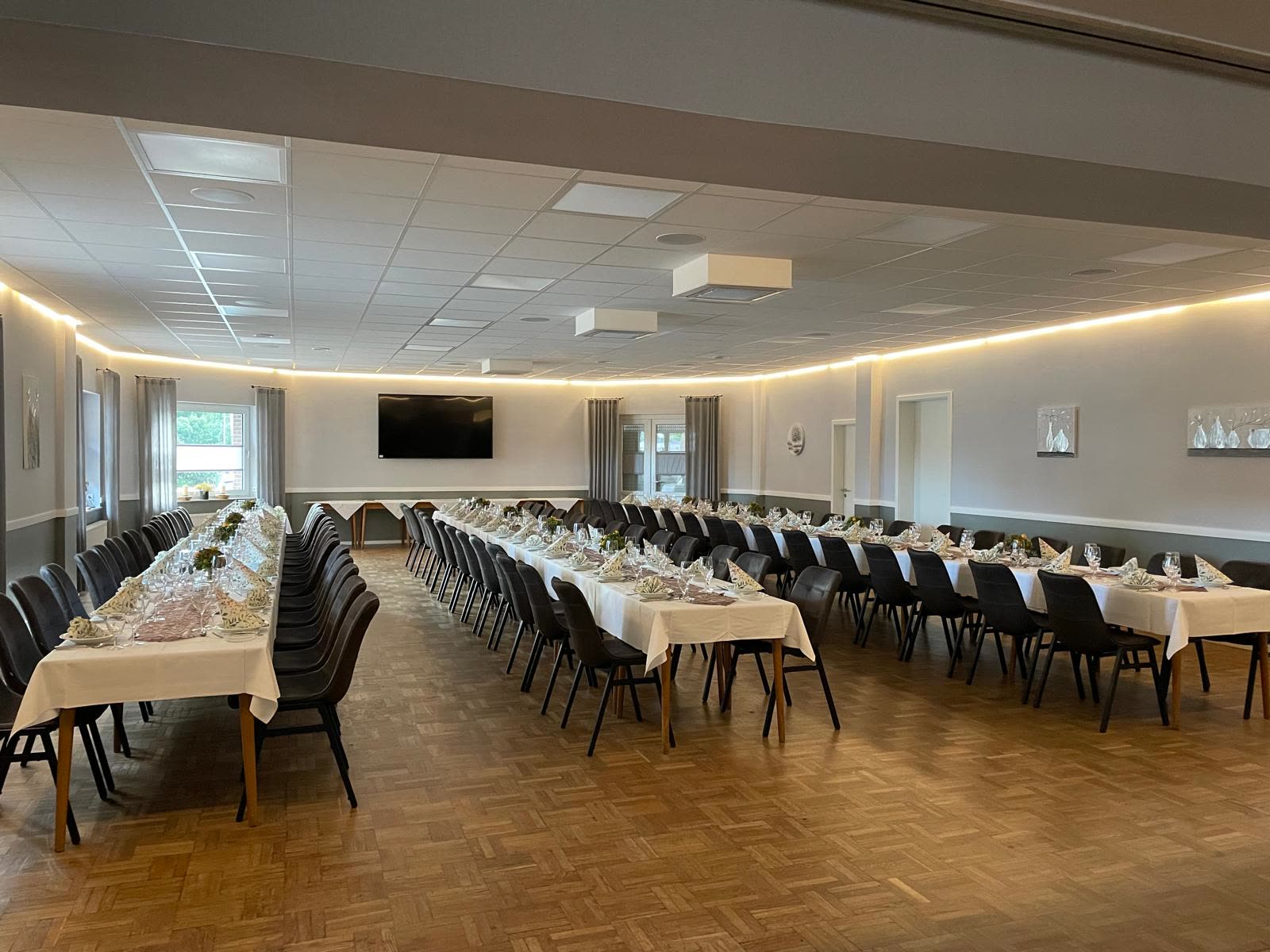 Großer Festsaal mit langen, eingedeckten Tafeln
